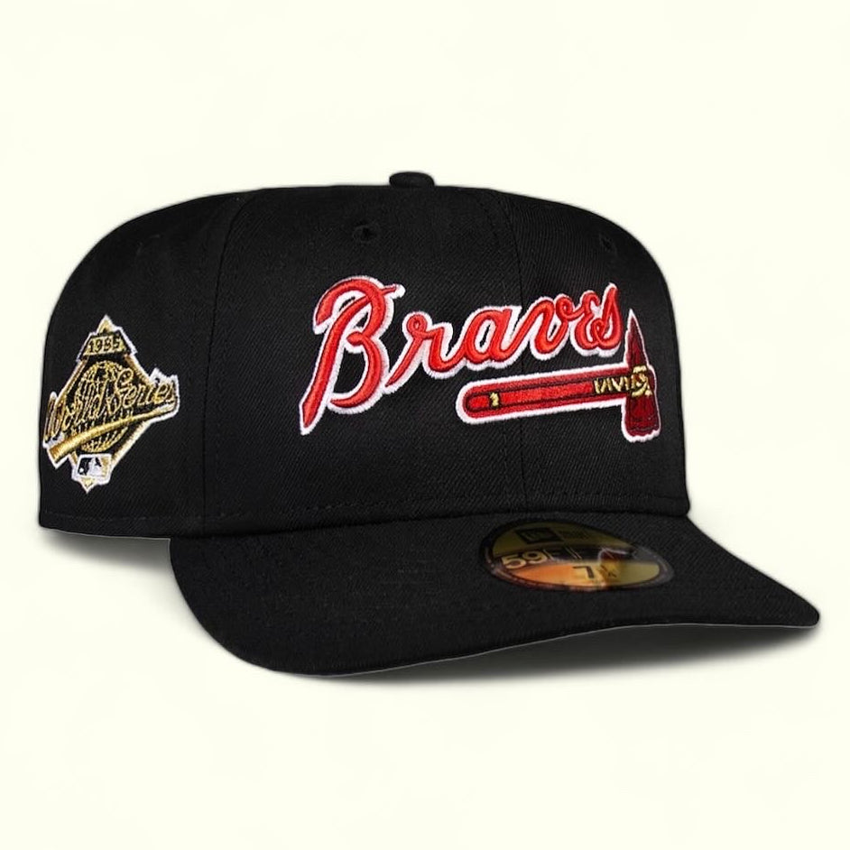 A black fitted cap with the Atlanta Braves script logo in red and a gold patch on the side.
